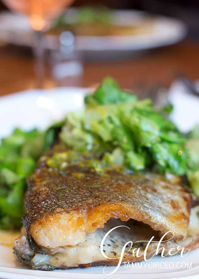 Whole cooked trout with salad in the background.