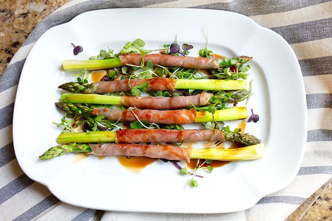 Sauteed proscuitto-wrapped asparagus on a bed of micro greens drizzled with balsamic vinegar