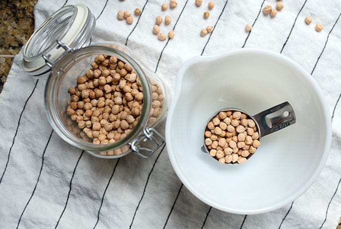 One-third cup of chickpeas in a bowl next to the canister of dried beans