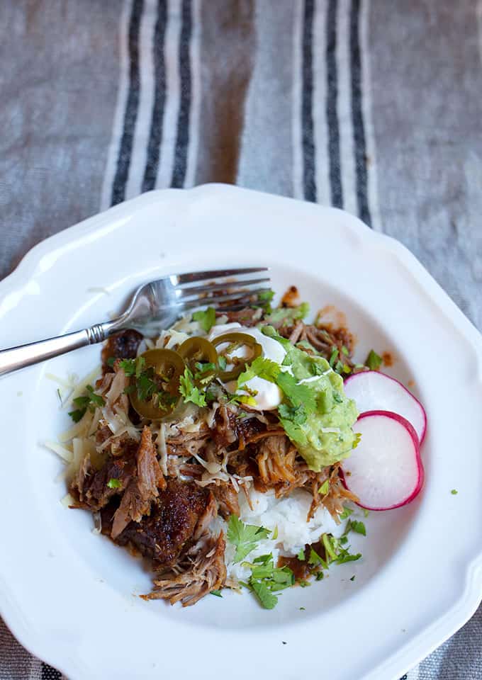 Bowl with rice, carnitas, guacamole, sour cream radishes, and jalapenos