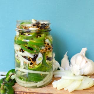 Pint jar of jalapenos, onion slices, coriander seeds, peppercorns, and garlic gloves
