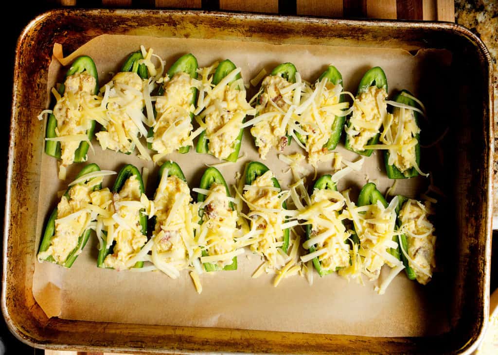 Jalapeno halves filled with cornbread and topped with shredded cheese