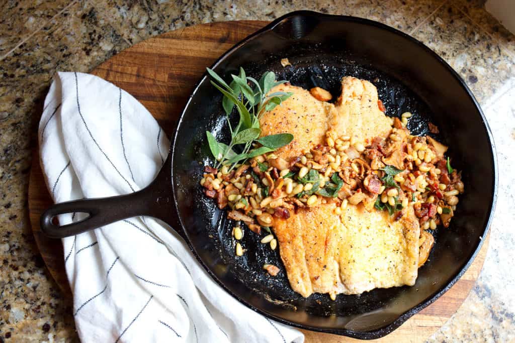 Two trout fillets in a cast iron skillet with the topping