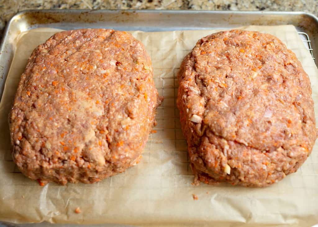 Formed meatloaves in a parchment lined baking rack on a baking sheet