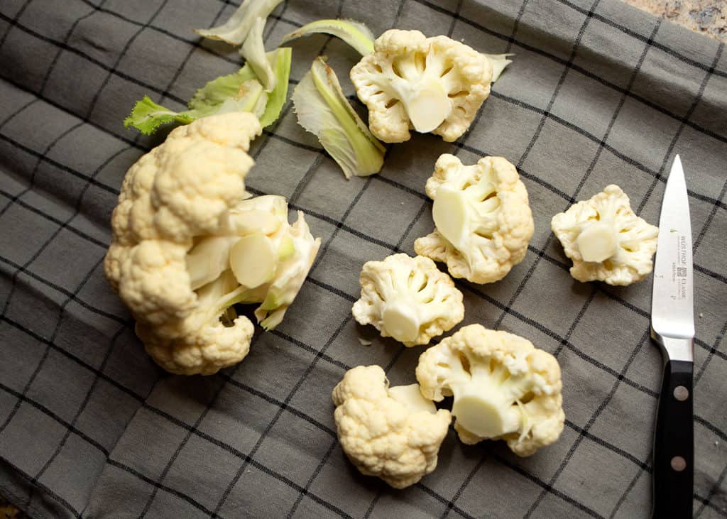 Trimming the cauliflower of the leaves and cutting small florets