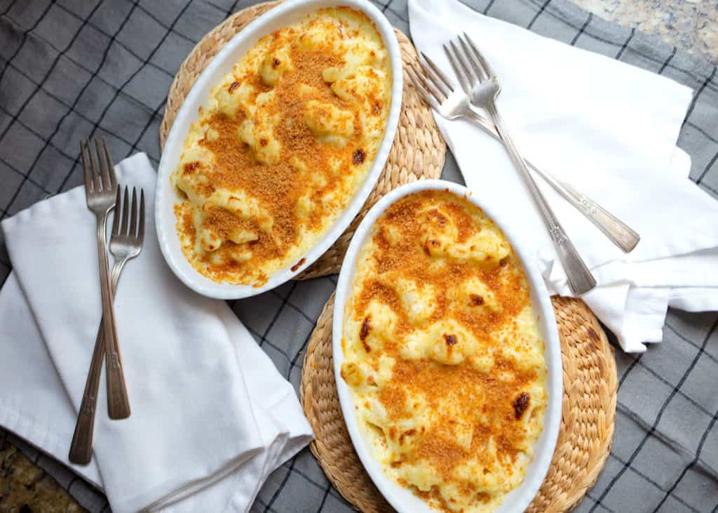 Two baking dishes of cauliflower gratin with napkins and forks on the side