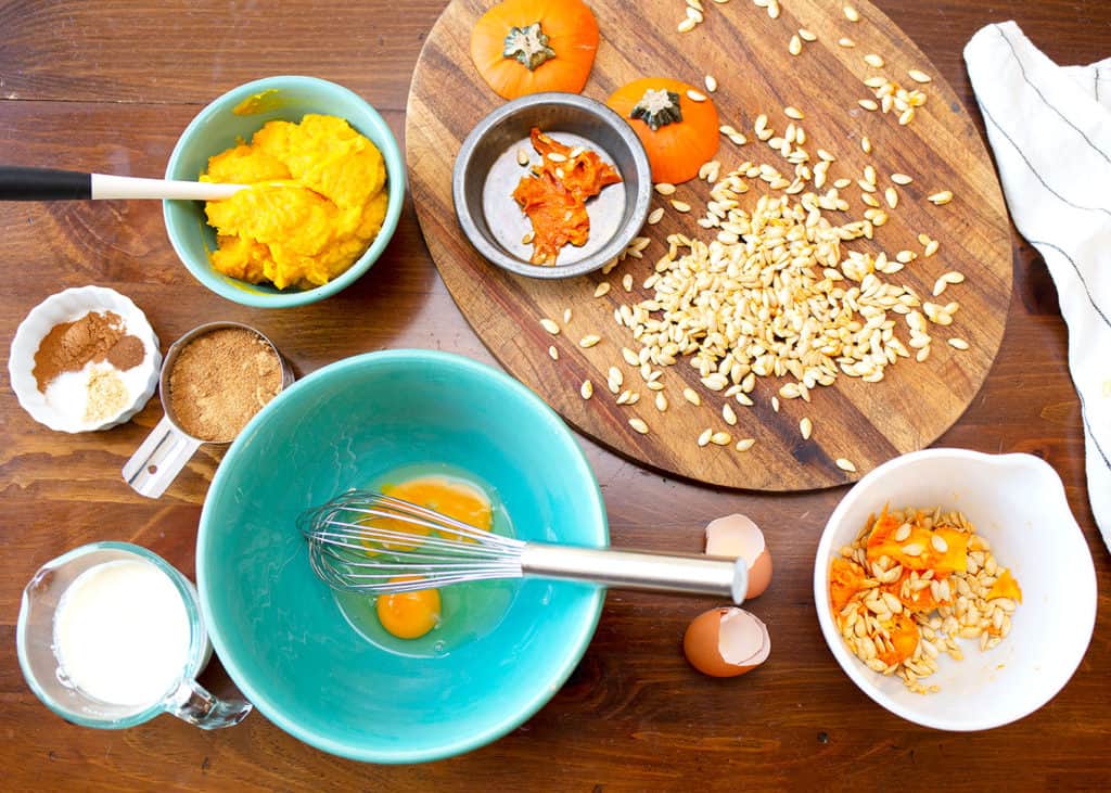 MIse-en-place of eggs in a large turquoise bowl, pumpkin puree, spices