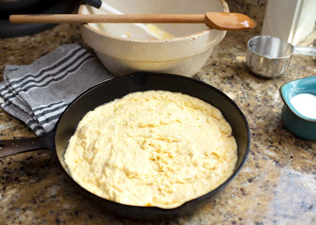 Cornbread batter poured into the hot cast iron skillet