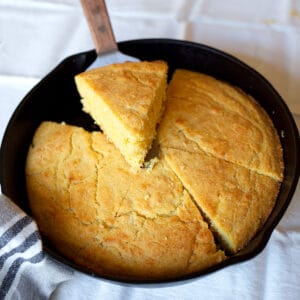 A cast iron skillet with Crunchy Cast Iron Cornbread cut into wedges