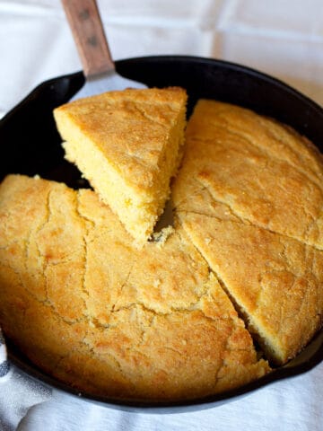A cast iron skillet with Crunchy Cast Iron Cornbread cut into wedges