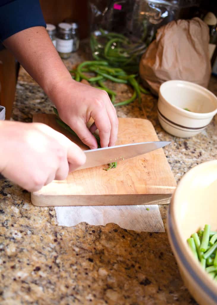 Trimming green beans with a large chef's knife