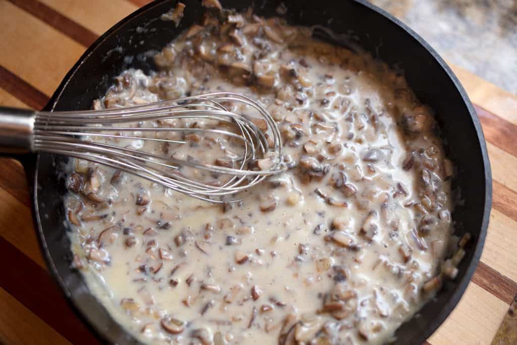 Mushroom gravy in a cast iron skillet with a whisk