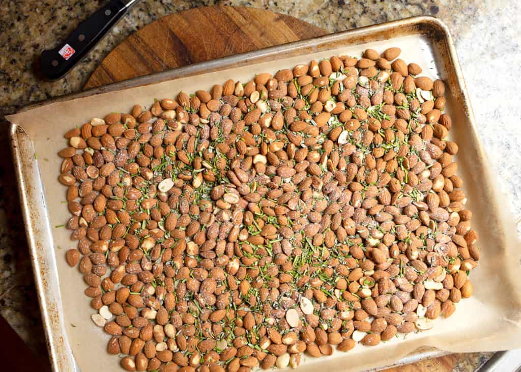 Raw almonds, rosemary, and salt on the parchment-lined baking sheet