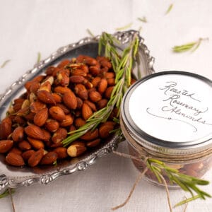 Roasted Rosemary Almonds in a silver serving tray with fresh rosemary littered about