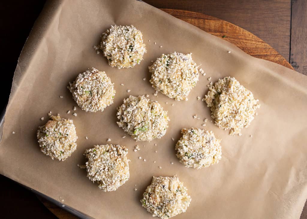 Nine beautiful crabcakes on a parchment-lined baking sheet