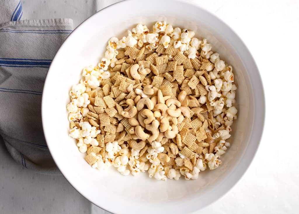 large white bowl with popcorn, chex cereal, and cashews