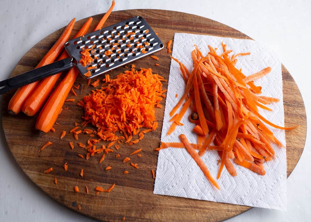 Carrots, peeled and grated on a wooden board