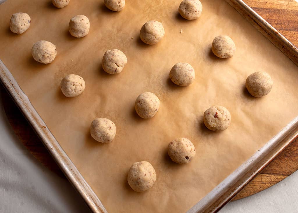 Cookies shaped into balls on a parchment lined baking sheet
