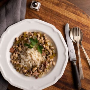 Flat soup bowl with rice covered with Hoppin' John - Black Eyed Peas and vintage silverware beside