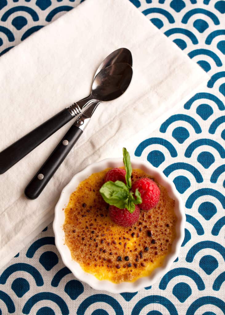 Creme Brulee garnished with fresh raspberries and mint ... two spoons