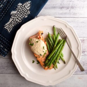 Serving of salmon on white plate with blue napkin