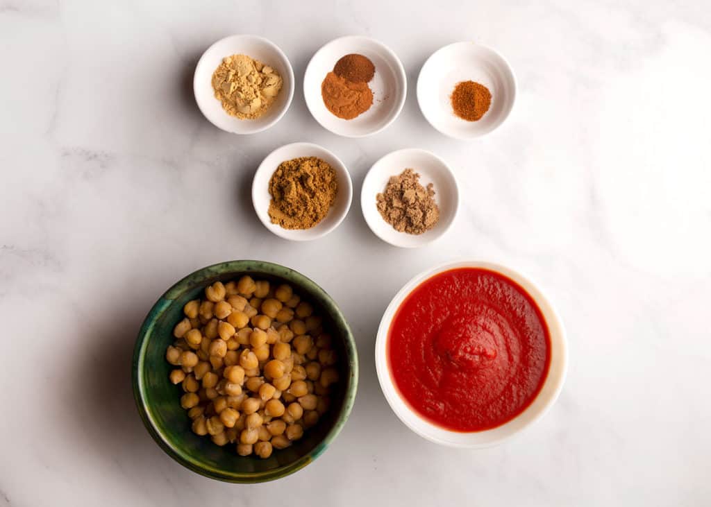 Spices, chickpeas and tomato sauce measured in separate bowls