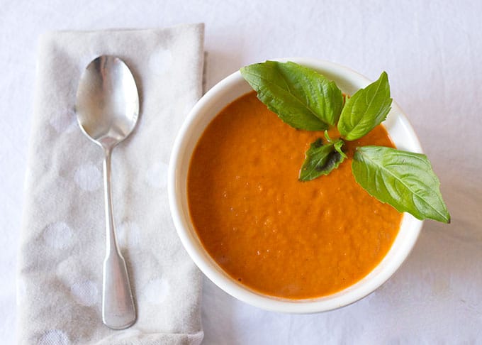 A serving of Roasted Tomato Soup with a basil leaf garnish