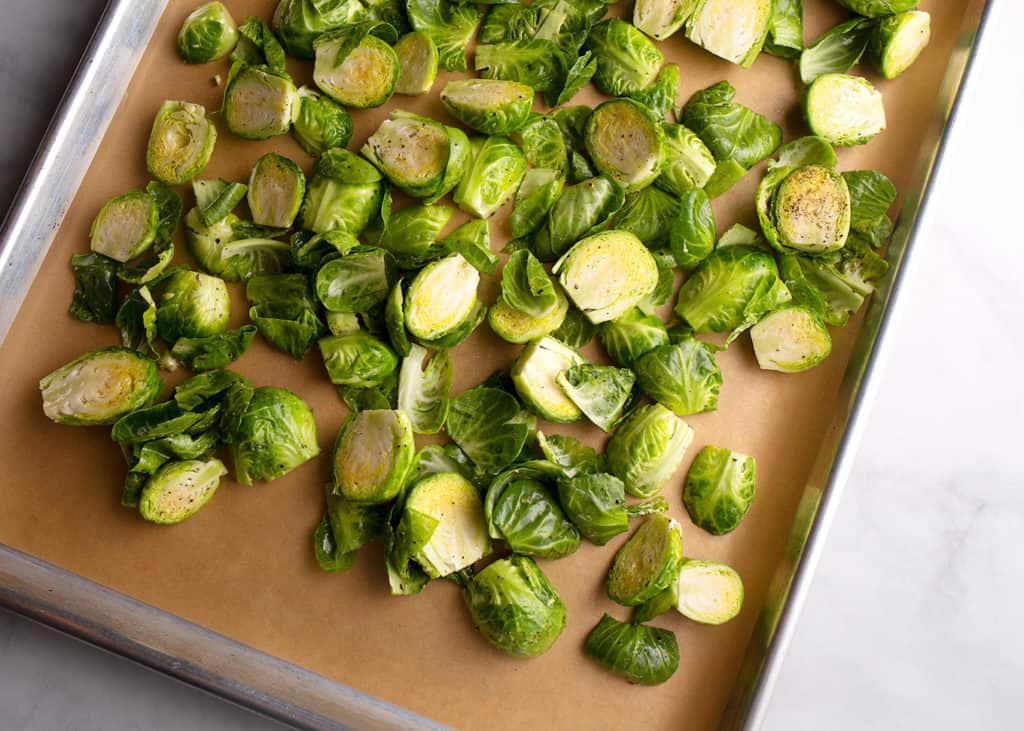 Oiled and seasoned Brussels Sprouts on a baking sheet
