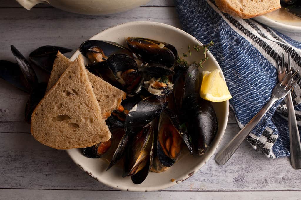 Bowl of Guinness & Cream Mussels with lemon wedge and bread