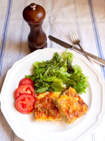 Two squares of Cheesy Egg Bake with a salad and tomato slices