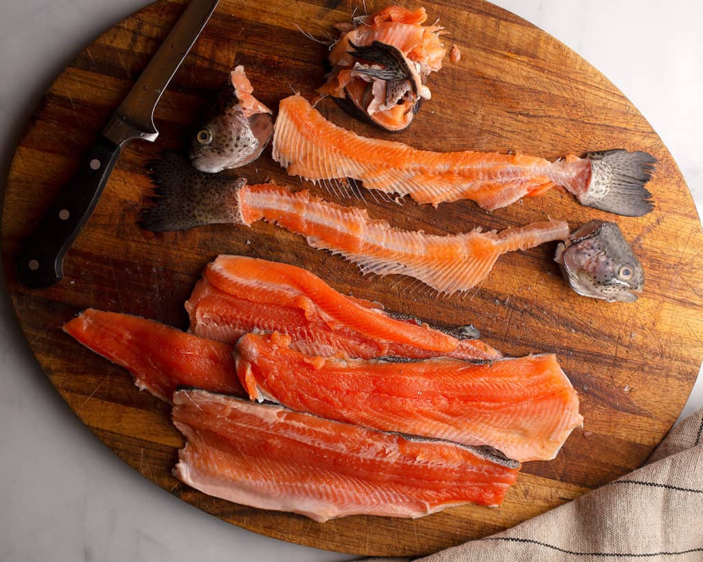 Two filleted whole rainbow trout on a cutting board