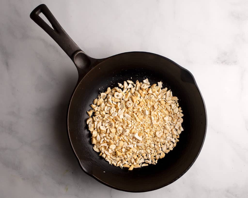 Chopped cashews in a cast iron chef's skillet to toast