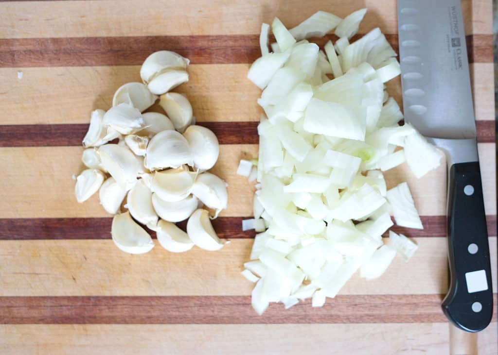 loads of garlic cloves and chopped onion on the cutting board