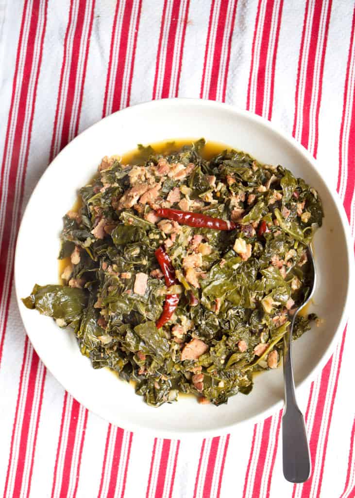 large bowl of braised greens on a red striped cloth