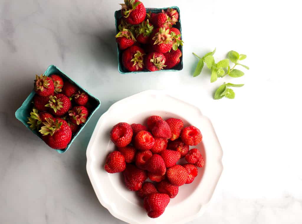Whole strawberries in baskets and hulled in a bowl