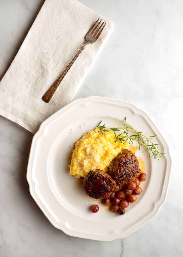 A serving of Italian sausage, grapes, and polenta