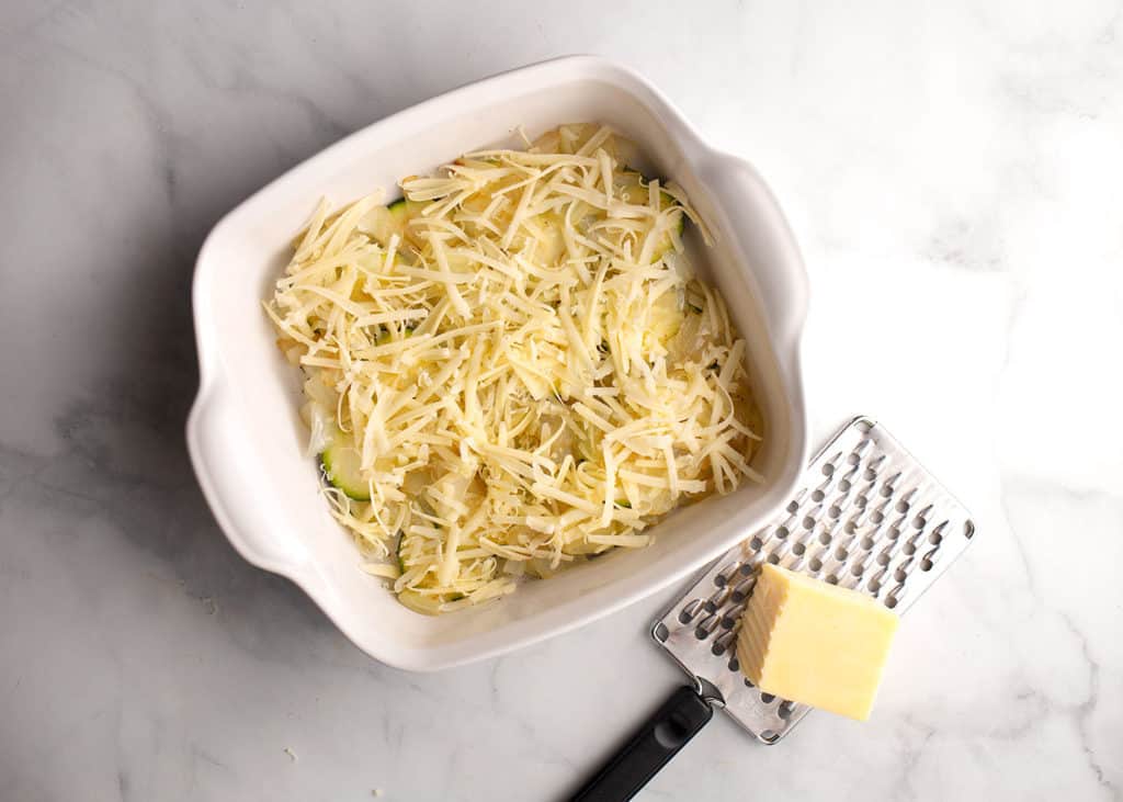 Cheese grated over zucchini and onions