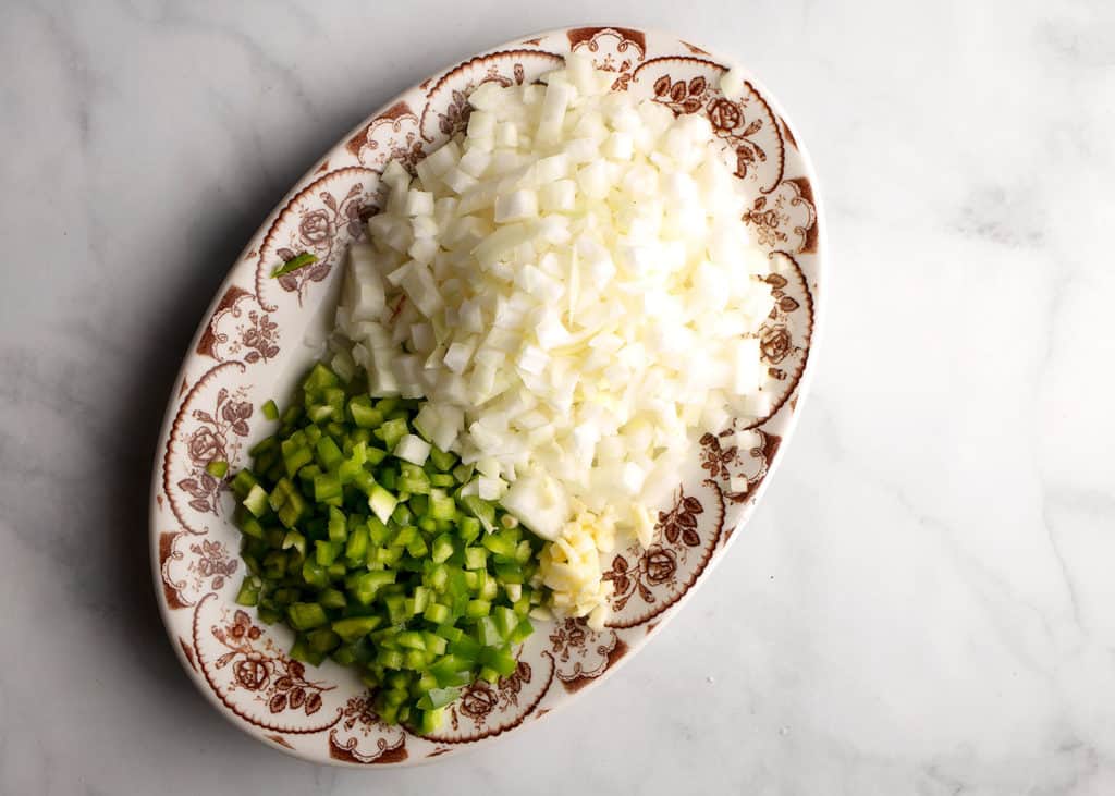 Chopped green pepper, onion, and garlic on a vintage platter