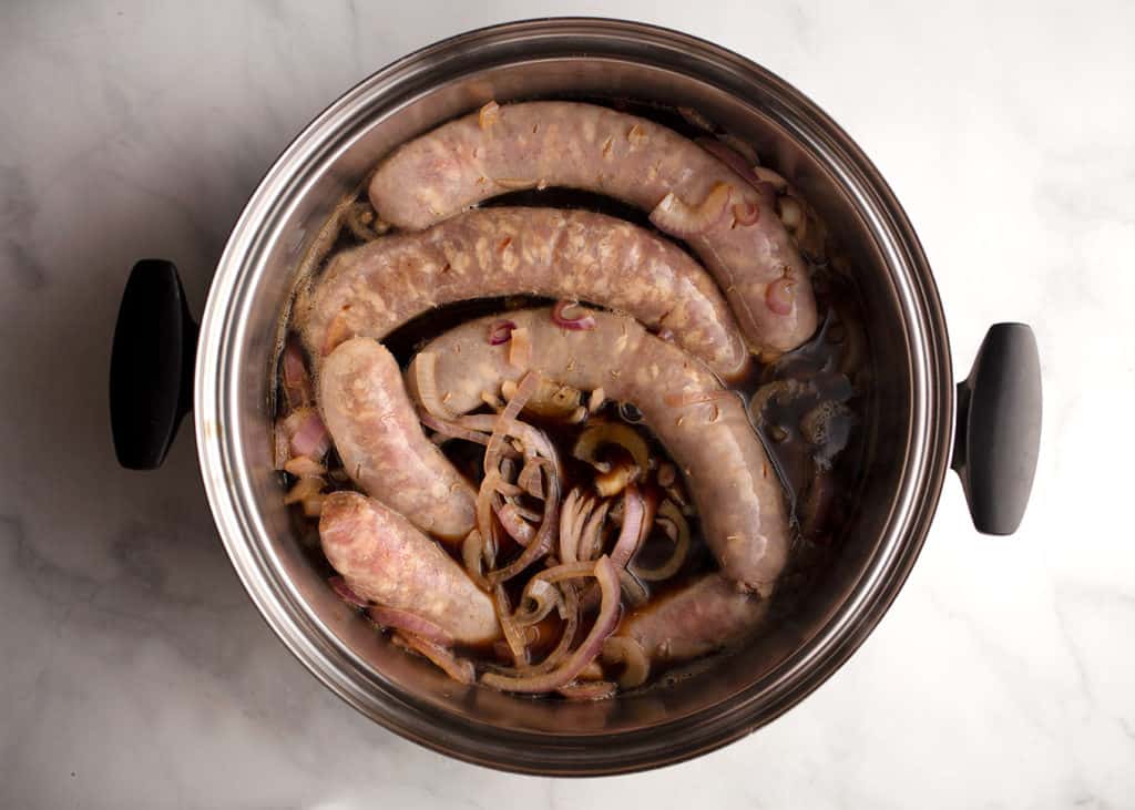 Bratwursts in the beer with purple onions