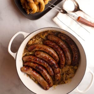 Featured image - grilled bratwursts in Dutch oven on top of sauerkraut