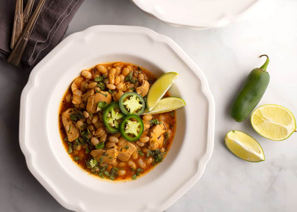 White Bean Pumpkin Chicken Chili with a jalapeno and lime wedges beside