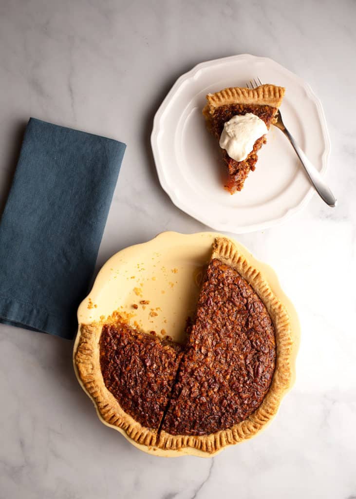 Classic Pecan Pie and a serving with cream on a dessert plate