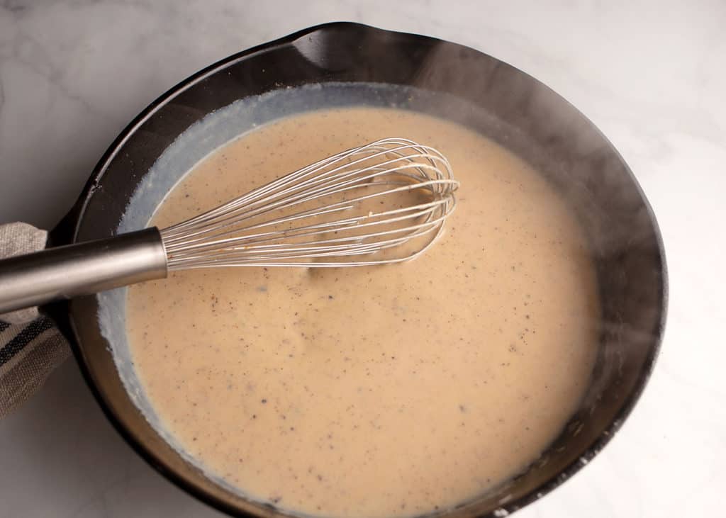 Whisking in the milk to make the gravy