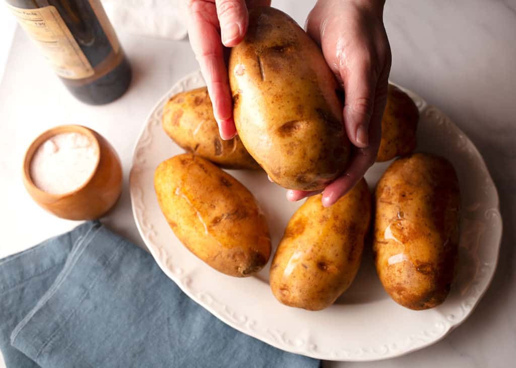Hands holding an oiled potato