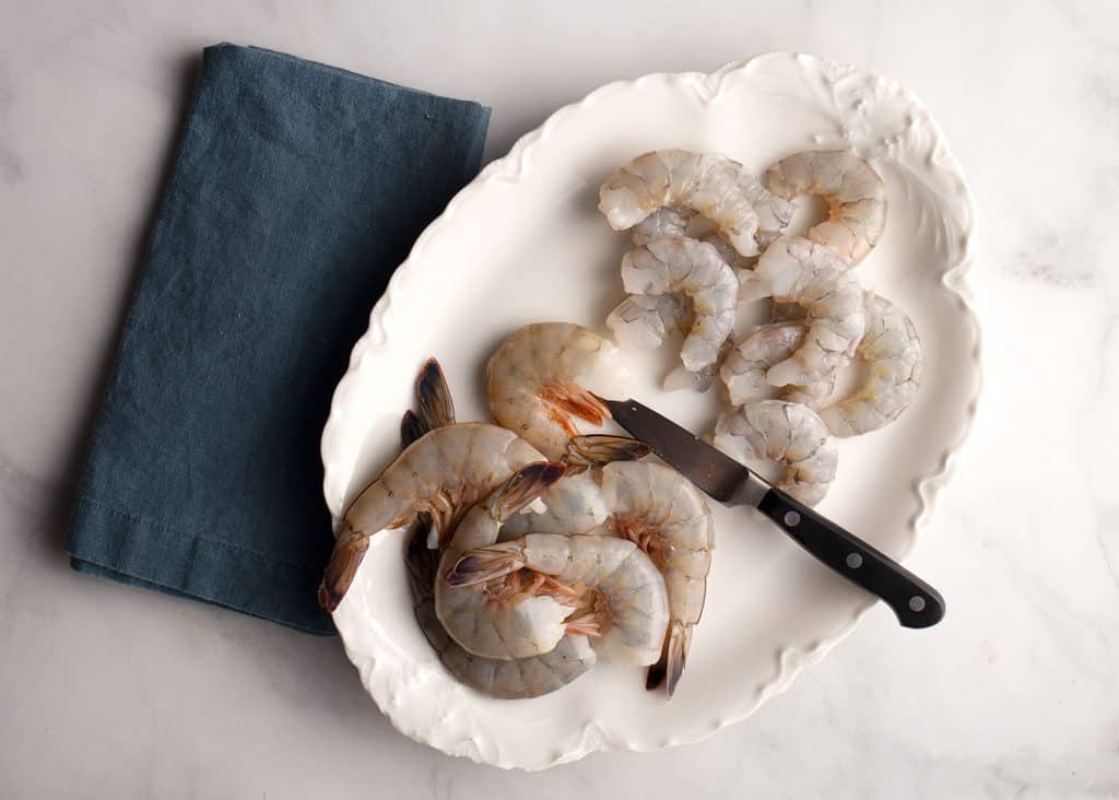 Platter with shell on shrimp on one side and peeled and deveined on the other.