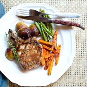 Pork Chop with Marsala Fig Sauce on a plate with figs, green beans, and carrots