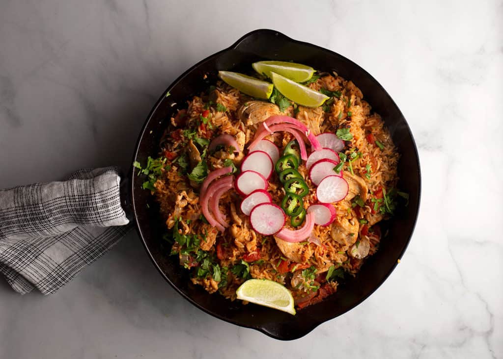 Chipotle Chicken & Rice garnished with limes, pickled onions, radishes, and jalapenos