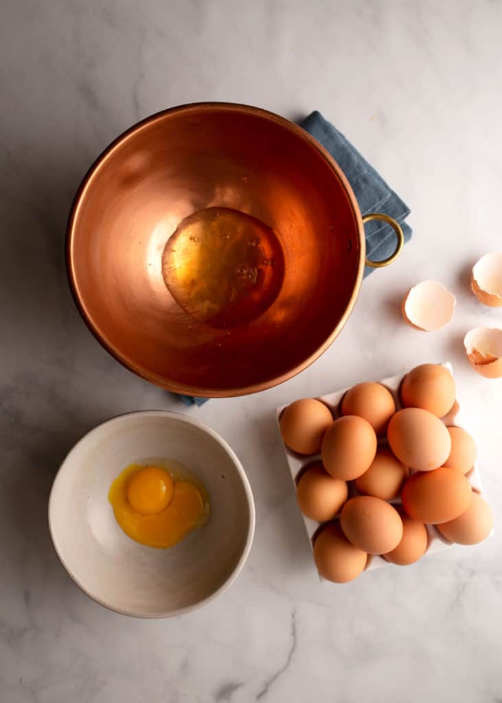Egg whites in copper bowl and yolks in smaller bowl
