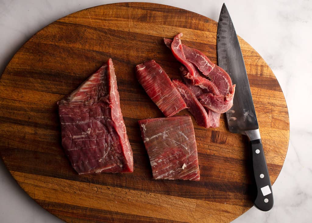 flank steak being cut into small strips