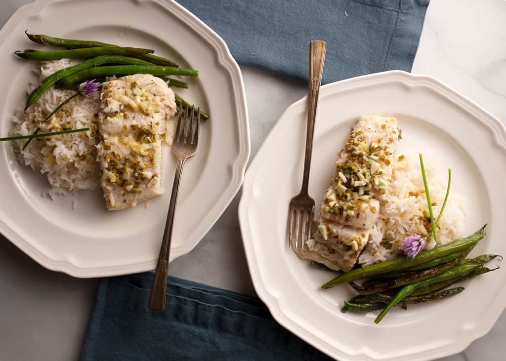 two servings of butter baked halibut with lemon, chives, and garlic
